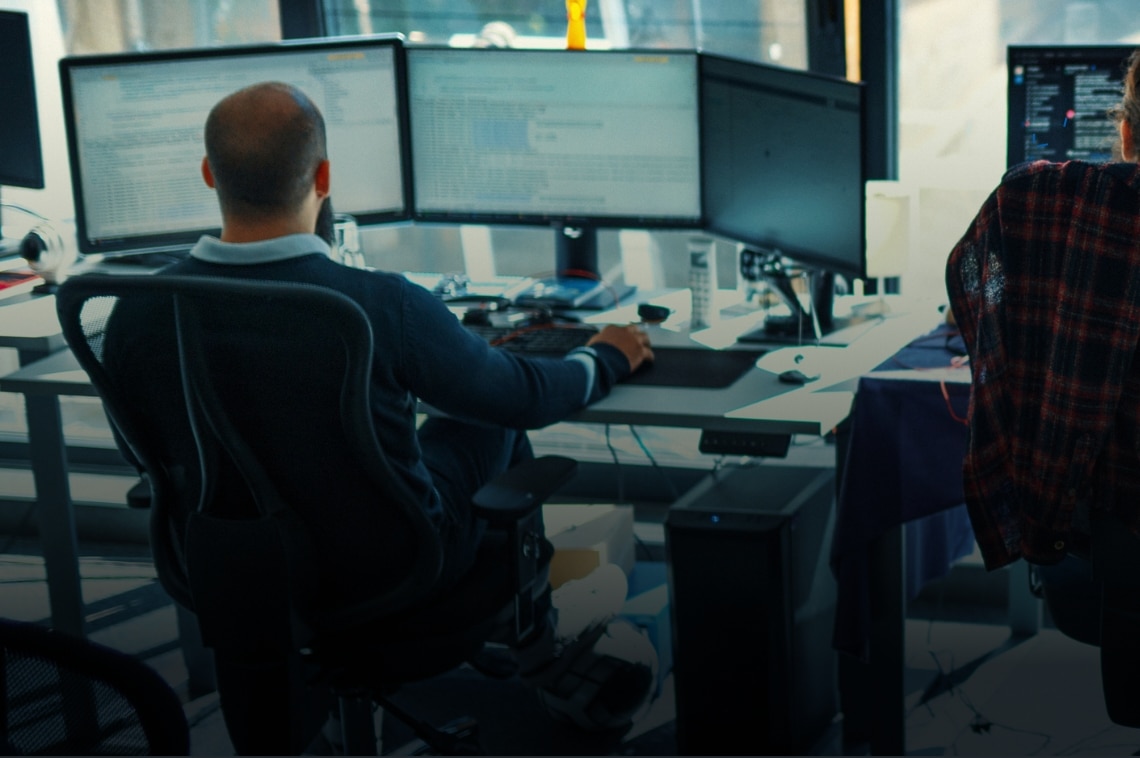 Man working in the office on three desktop monitors